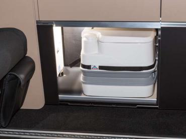 Die mobile Brandrup "Porta Potti 335 Qube" Toilette mit angebrachtem Haltegurt und praktischem Schlaufengriff, positioniert in einer Camping-Umgebung.